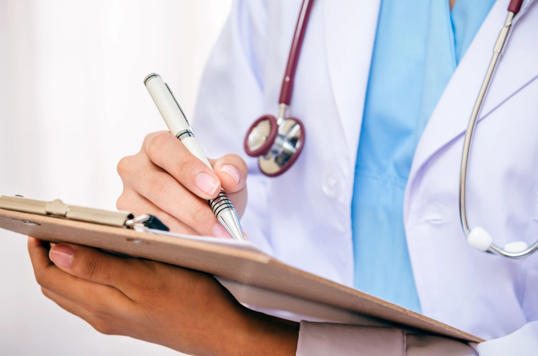 Doctor with stethoscope writing on a clipboard