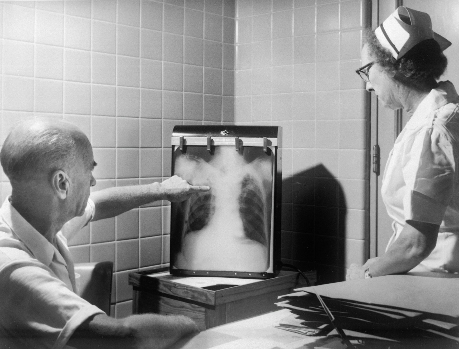 A physician and a nurse reviewing a chest x-ray on a light box