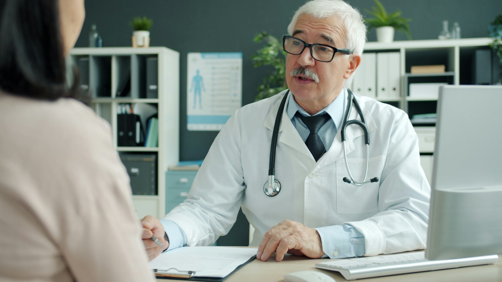 A doctor talking with a patient across a desk in a medical office