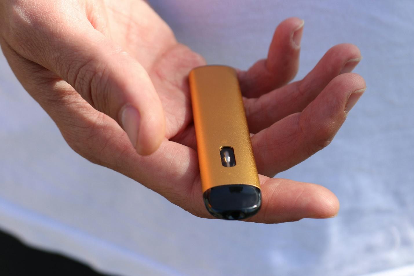 Close-up of a hand holding a gold THC vape device