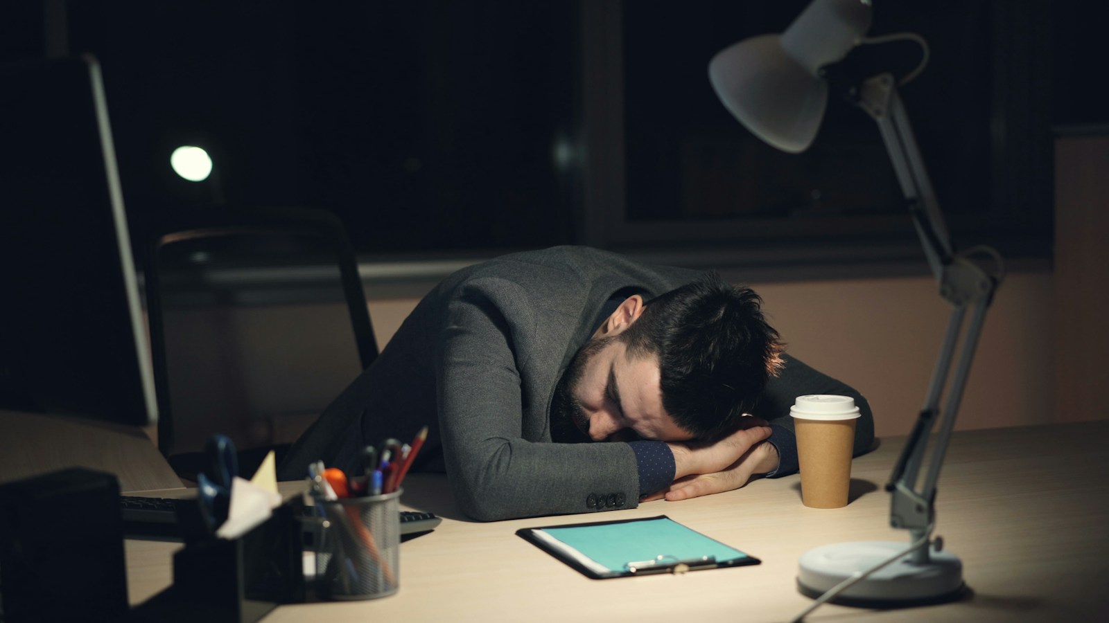 Man sleeping at desk with coffee and tablet